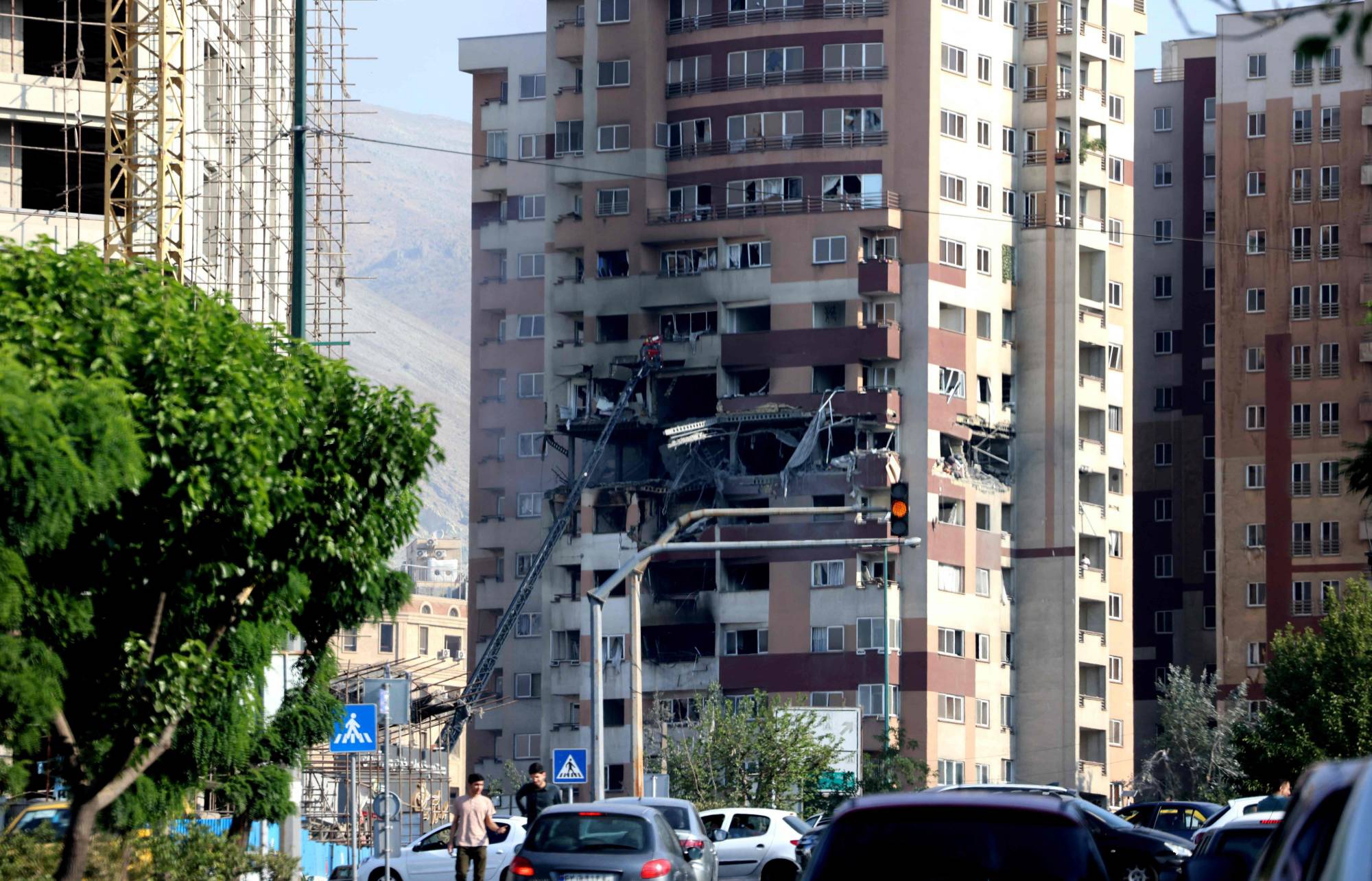 أشخاص يسيرون أمام مبنى استهدفه هجوم إسرائيلي في العاصمة الإيرانية طهران (أ.ف.ب) أشخاص يسيرون أمام مبنى استهدفه هجوم إسرائيلي في العاصمة الإيرانية طهران (أ.ف.ب)